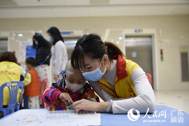 广州市金丝带特殊儿童家长互助中心工作人员正在教白血病患儿画画.