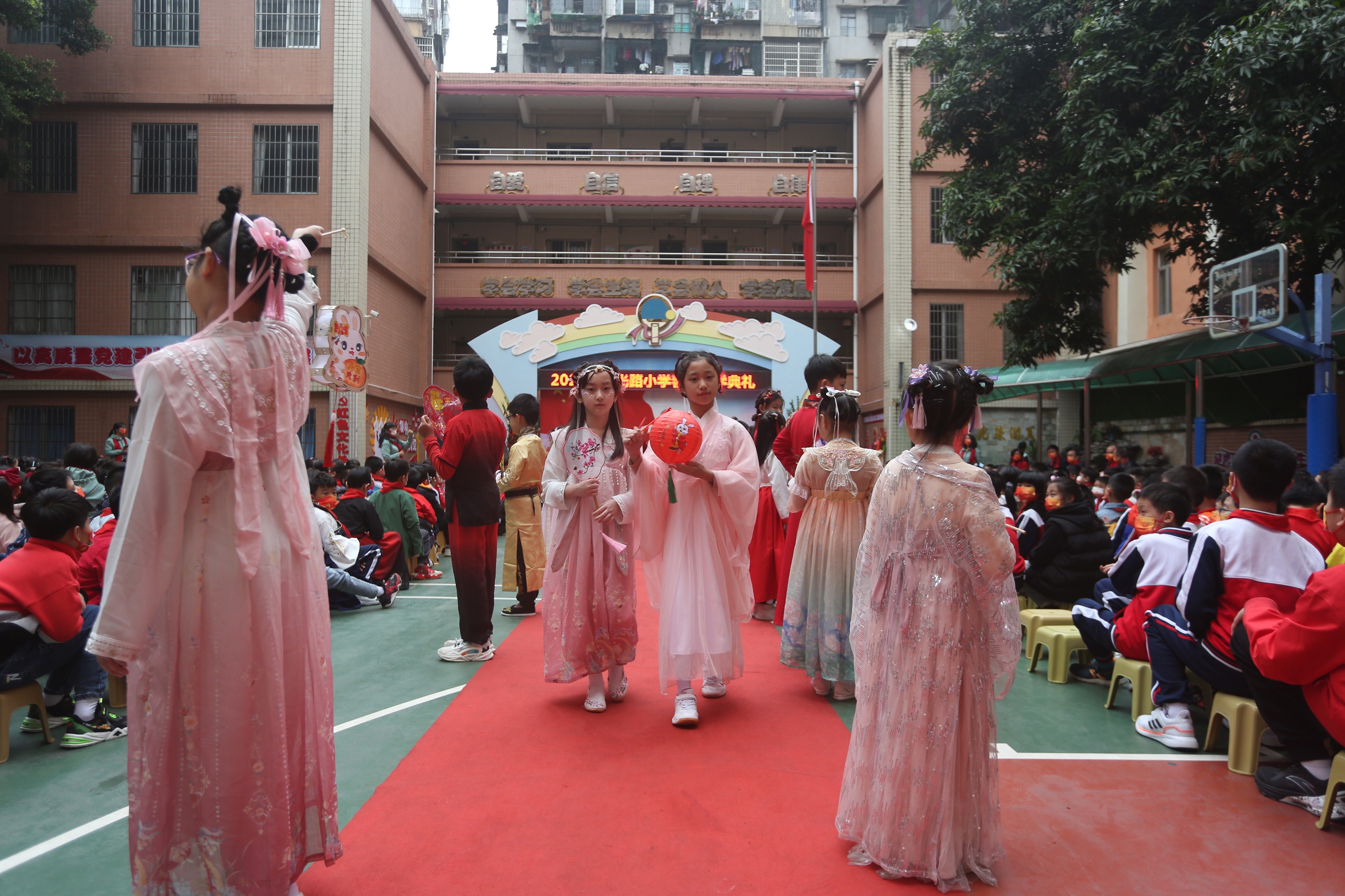 广府庙会进校园活动，学生们穿着汉服拿着花灯走进操场。钟涌摄