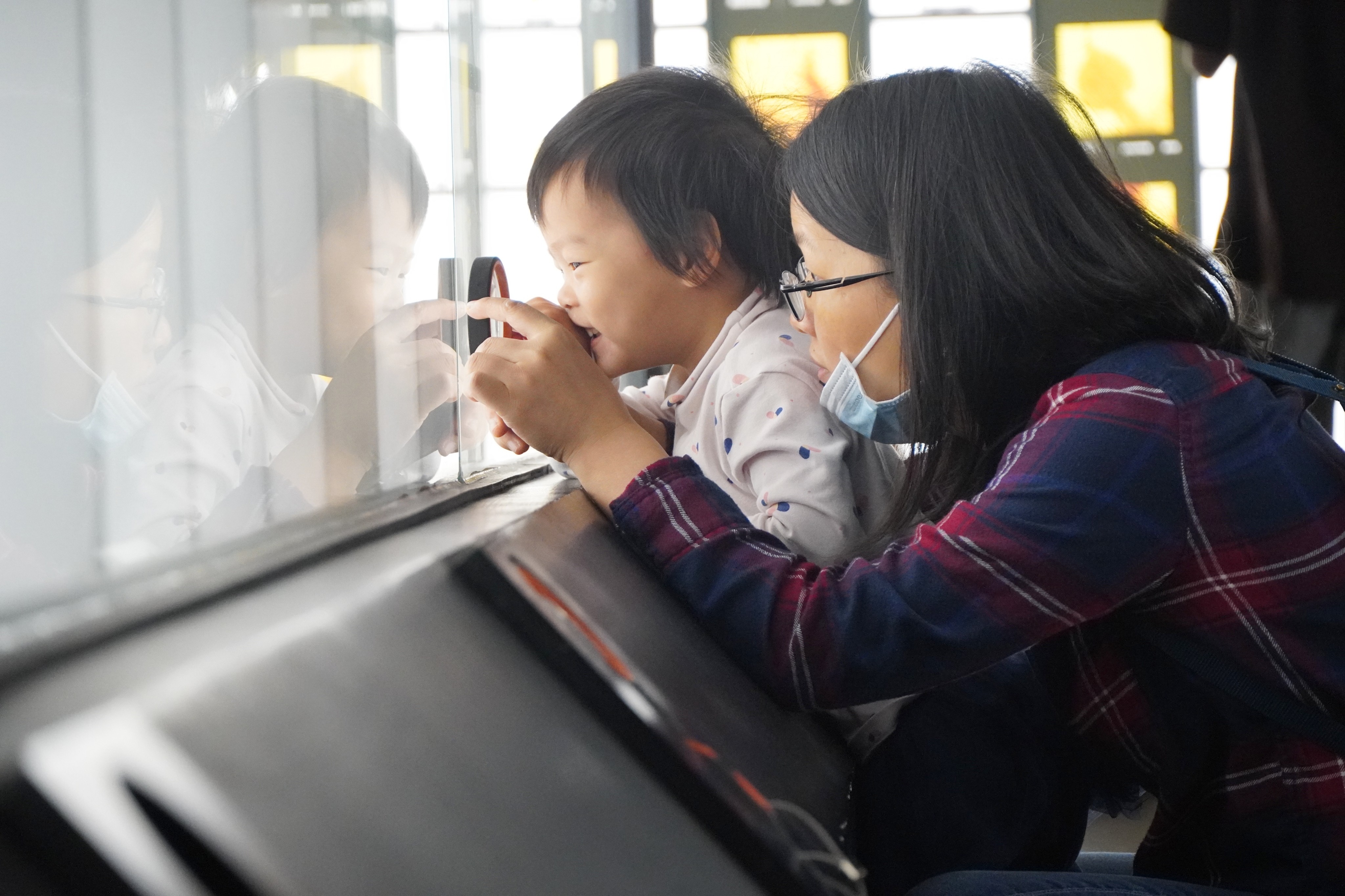 一位孩童在母亲的带领下，用放大镜观察琥珀的形态。王雅蝶 摄