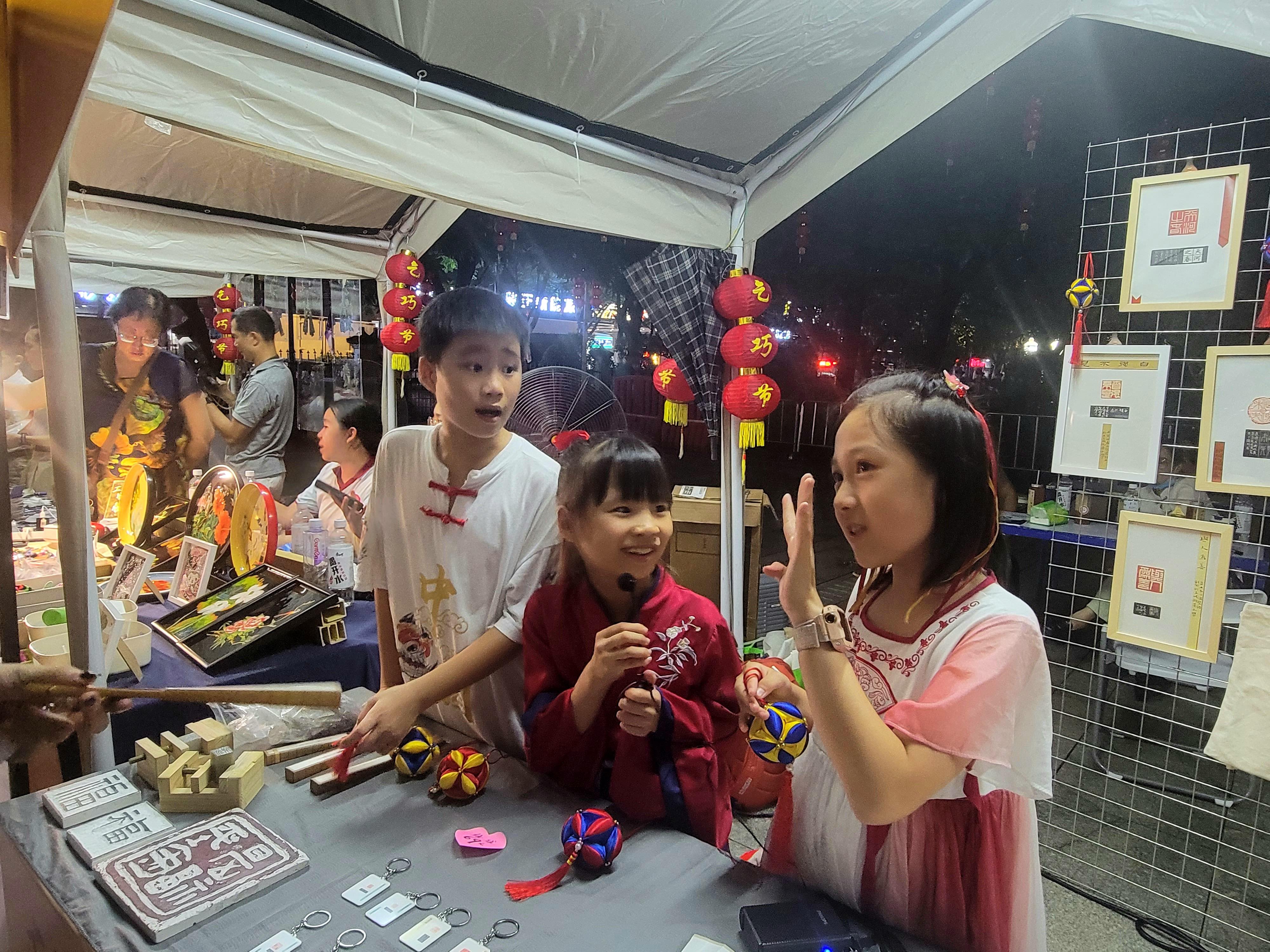 在非遗创意集市，广州本地小学生向市民游客介绍师生制作的特色篆刻商品。人民网 宁玉瑛摄