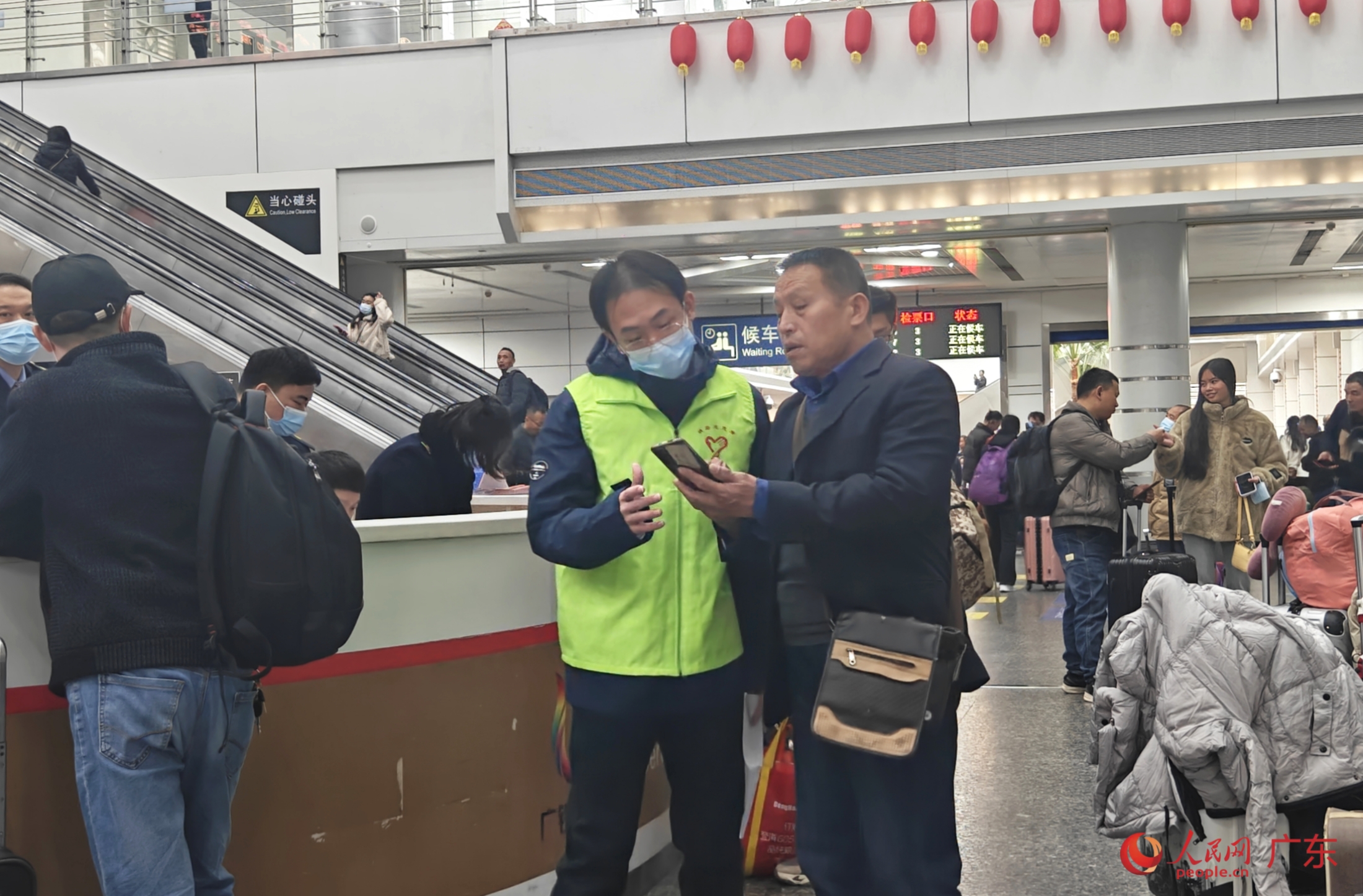 1月26日，在广州东站，志愿者解答旅客疑问。人民网 王雅蝶摄