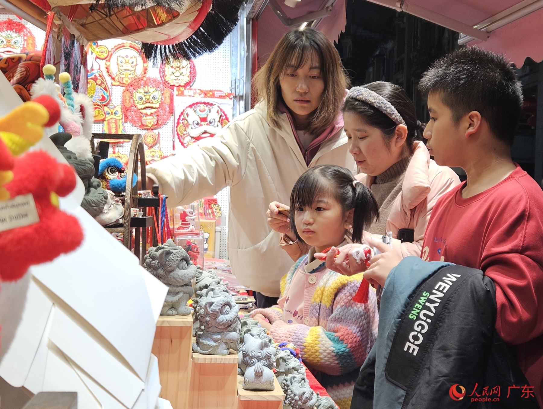 除夕夜，广州北京路步行街沿街店铺的龙元素公仔引来小朋友关注。人民网 张永生摄