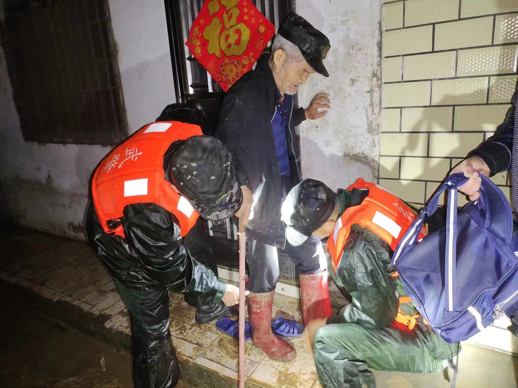 在韶关,广东武警官兵为老人穿上雨靴,做好转移准备。武警广东总队供图