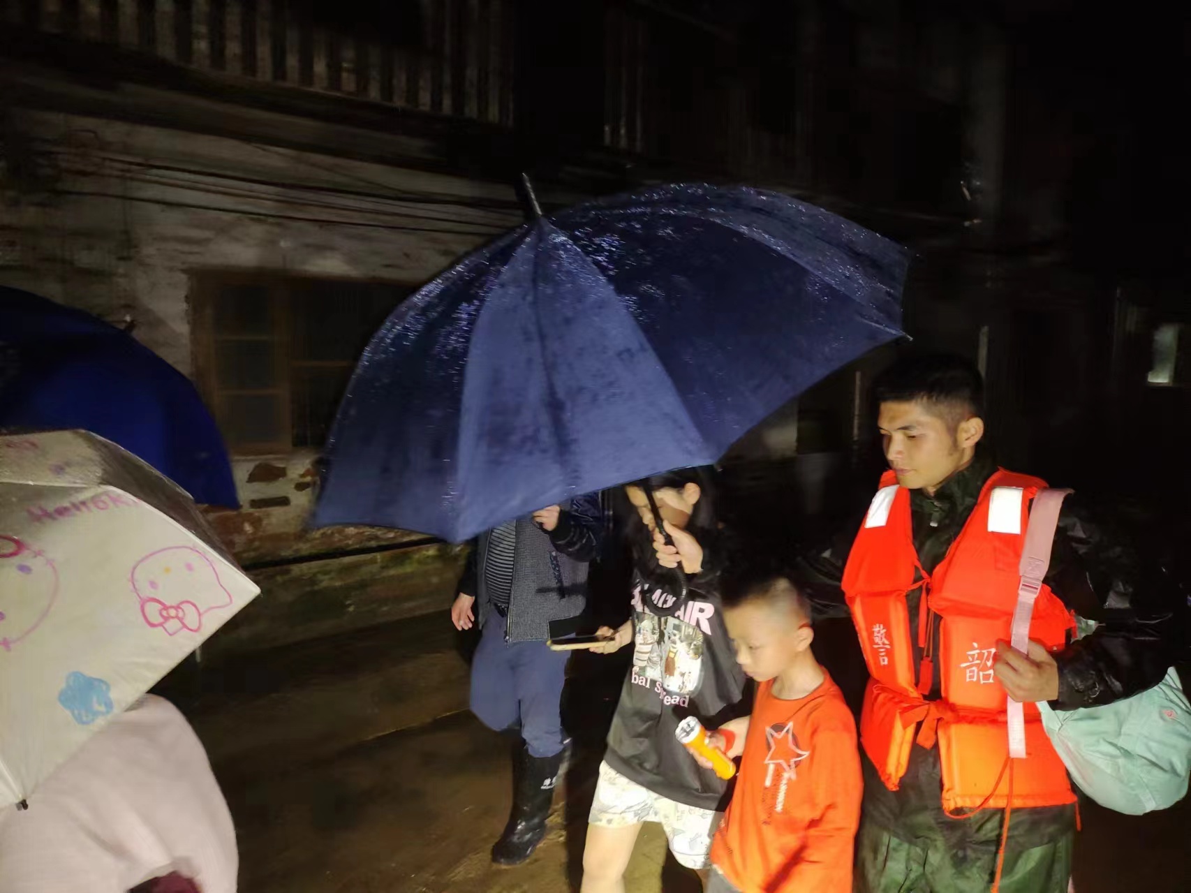 在韶關，廣東武警官兵為群眾撐起雨傘，帶領其前往安全地帶。武警廣東總隊供圖