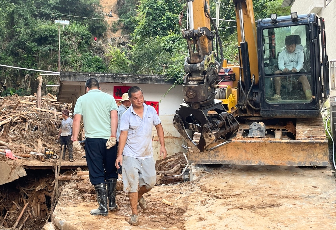 6月28日，平遠縣泗水鎮圩鎮，人們正在清理山體滑坡帶下來的泥石等。人民網 張永生攝