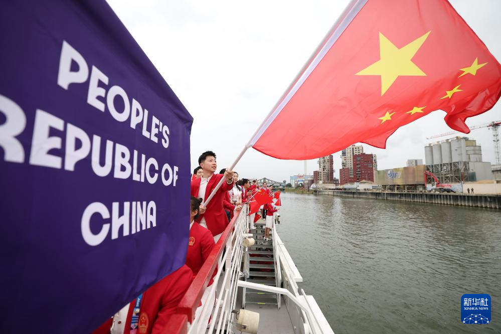 7月26日，中国体育代表团旗手乒乓球选手马龙（前）在开幕式前挥舞国旗。新华社记者 曹灿 摄
