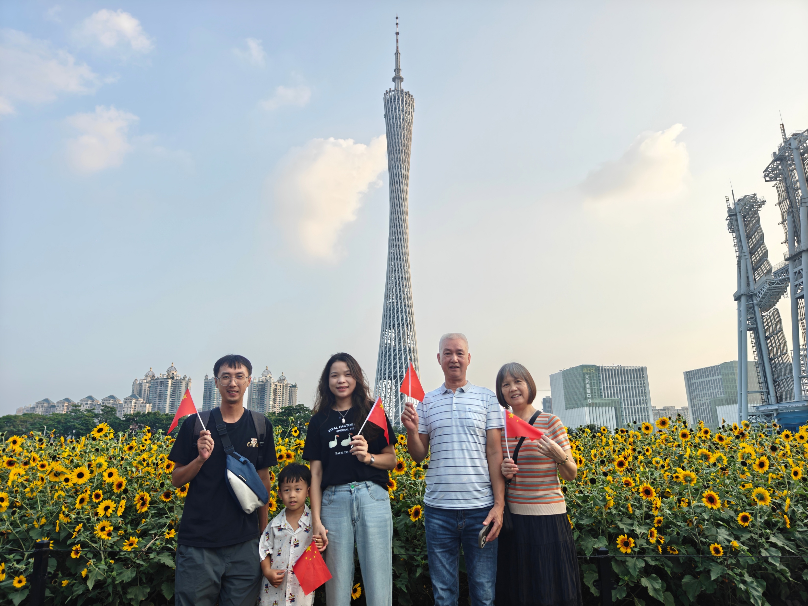 國慶將至，在廣州市海心沙亞運公園的向日葵花海，市民游客手持五星紅旗拍照。人民網 王雅蝶攝