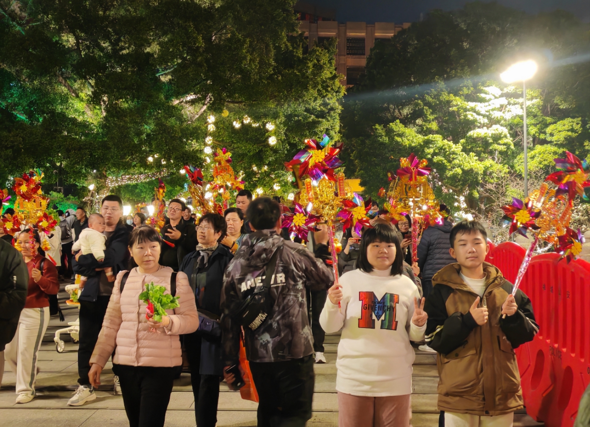 人们手持风车行通济，寓意顺风顺水。人民网 宁玉瑛摄