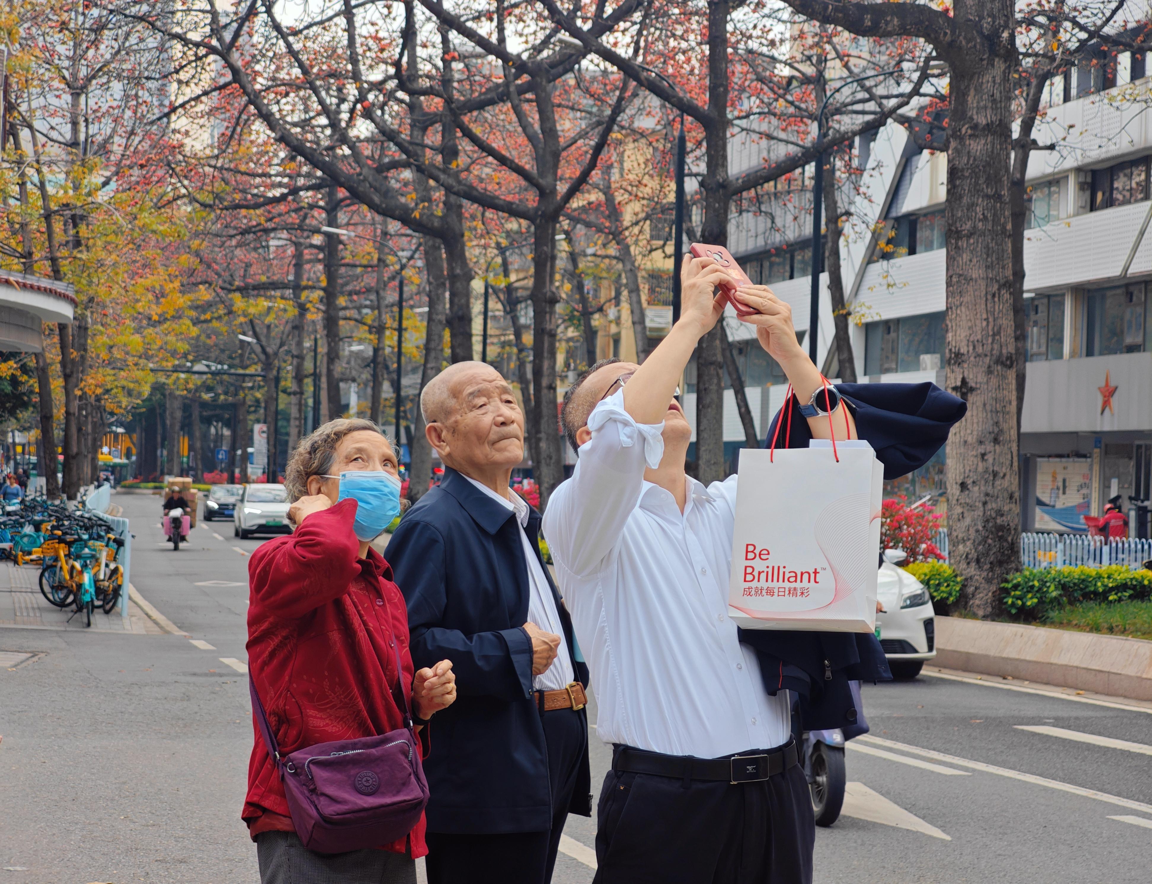 走出广州起义烈士陵园，一家人在陵园西路上拍摄木棉绽放。人民网 朴馨语摄