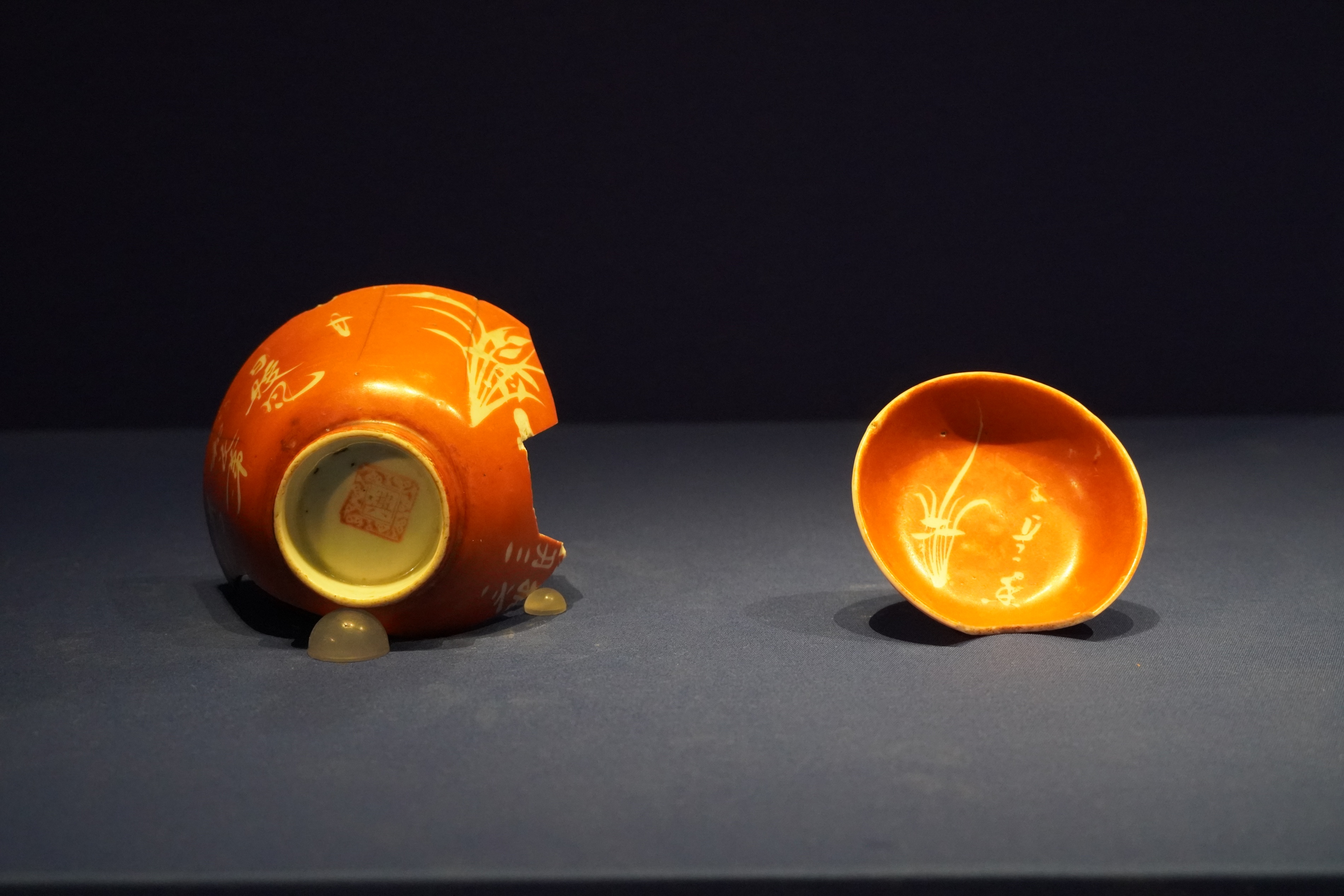 展览现场的矾红兰花诗文杯、诗文碟（清代，公元1644-1911年），越秀区府前路1号工地出土。人民网 王雅蝶摄