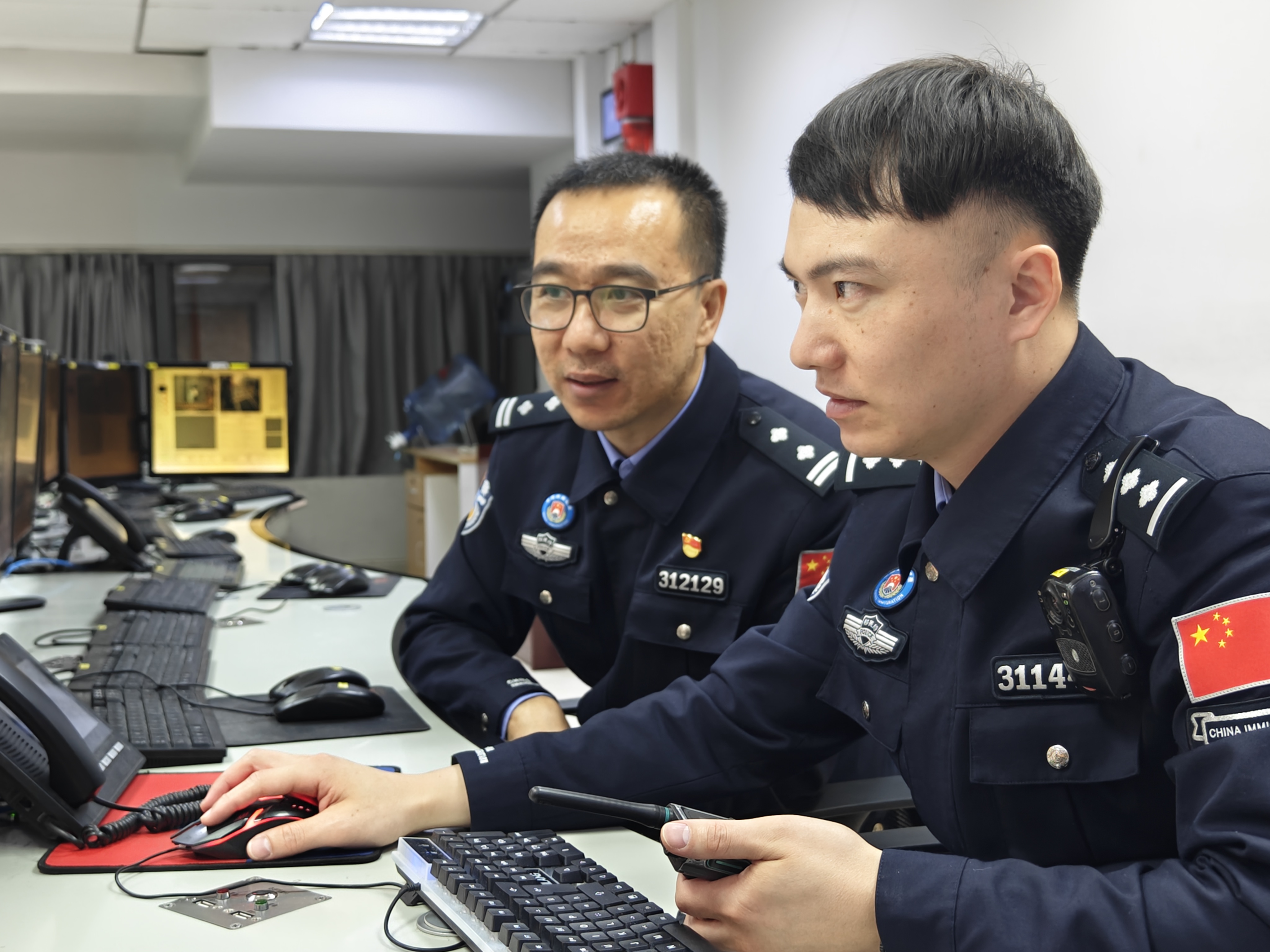 春运进行时，付银鹏（左）向值班民警收集关于边检集中监控系统运行的意见。人民网记者 王雅蝶摄