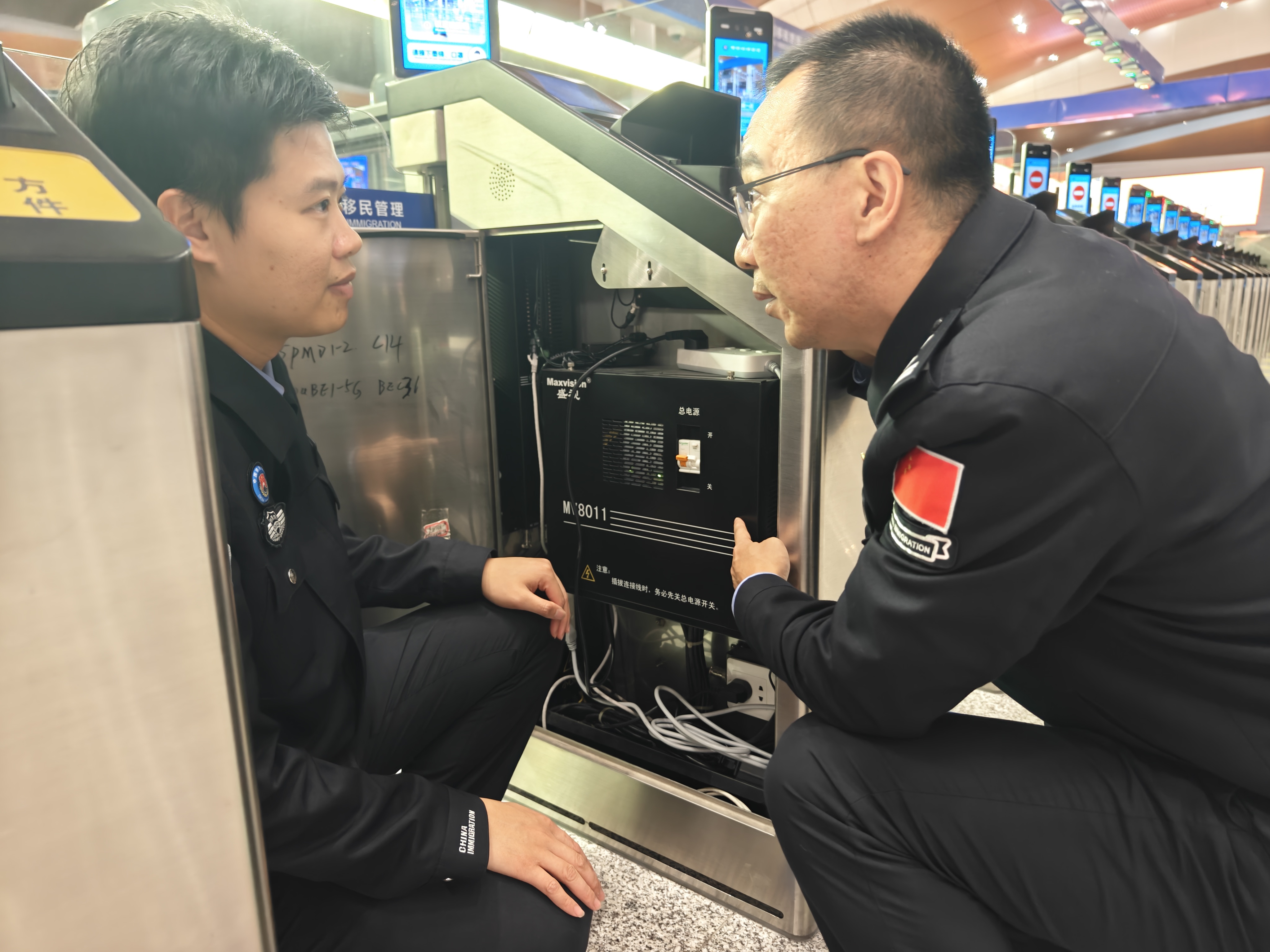 趁客流高峰過去,付銀鵬(右)和同事檢查通關設備電池運行情況。人民網記者 王雅蝶攝