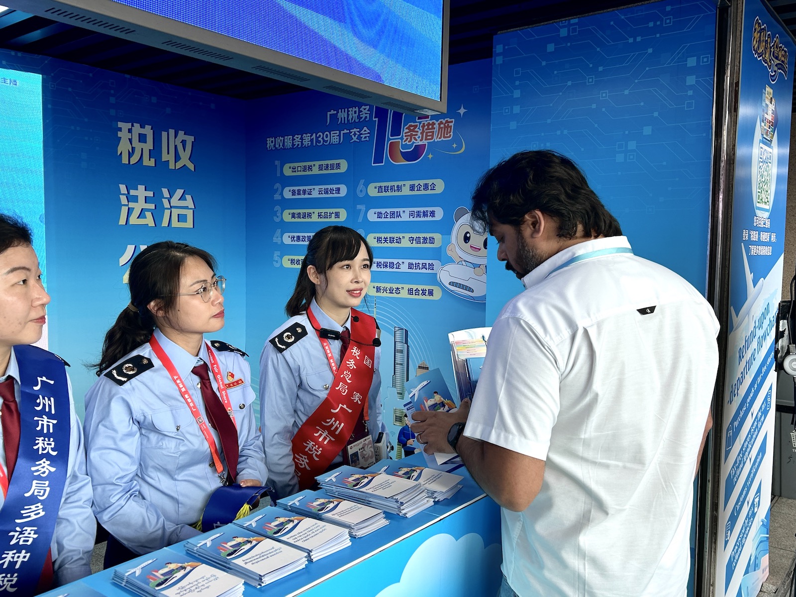 广交会现场,税收服务驿站工作人员为海外客商解答疑惑。实习生 兰航宇摄