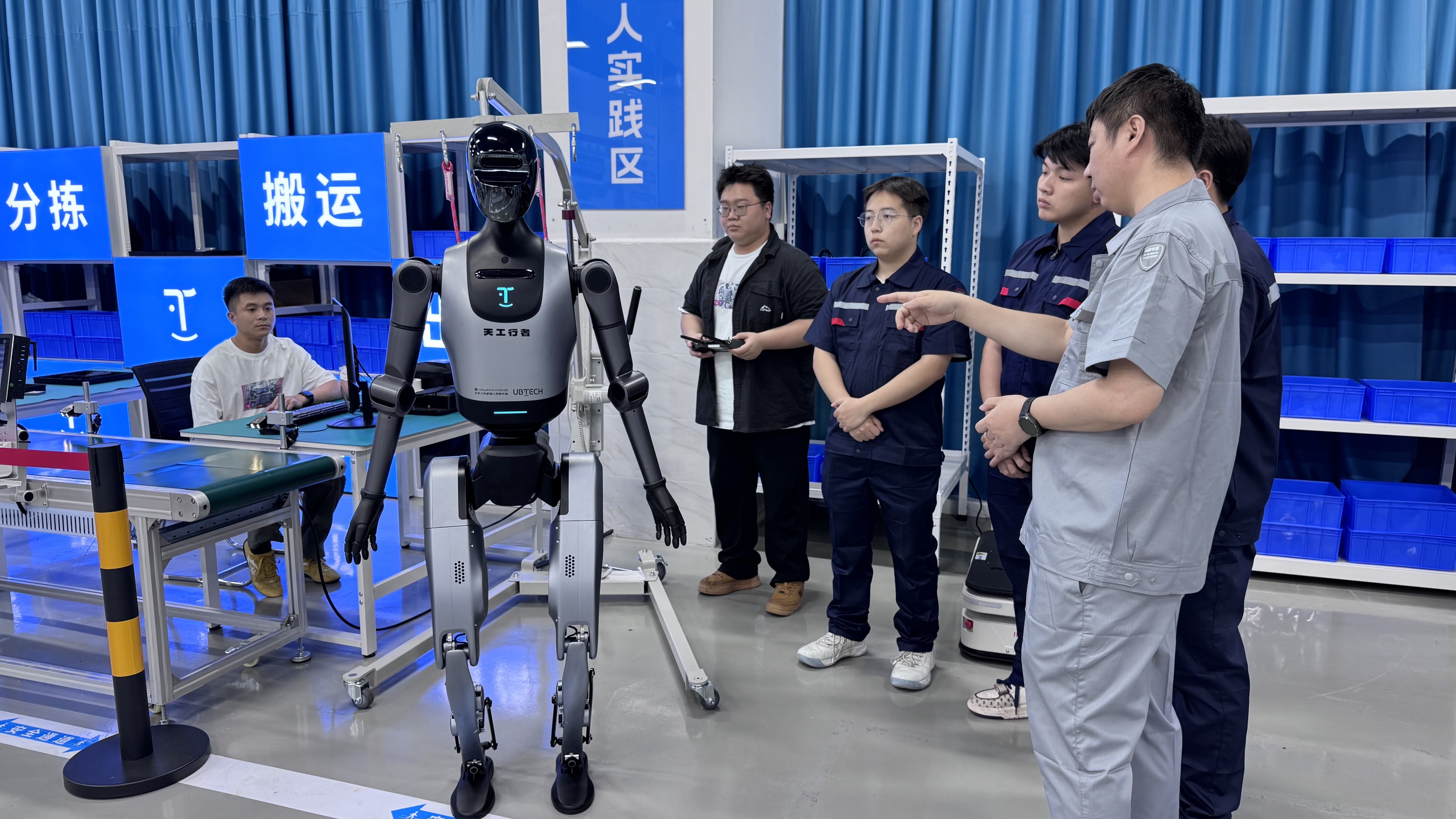广东科学技术职业学院机器人学院实践中心内，团队正在人形机器人前开展实训教学与技术交流。人民网记者 李昊洋摄