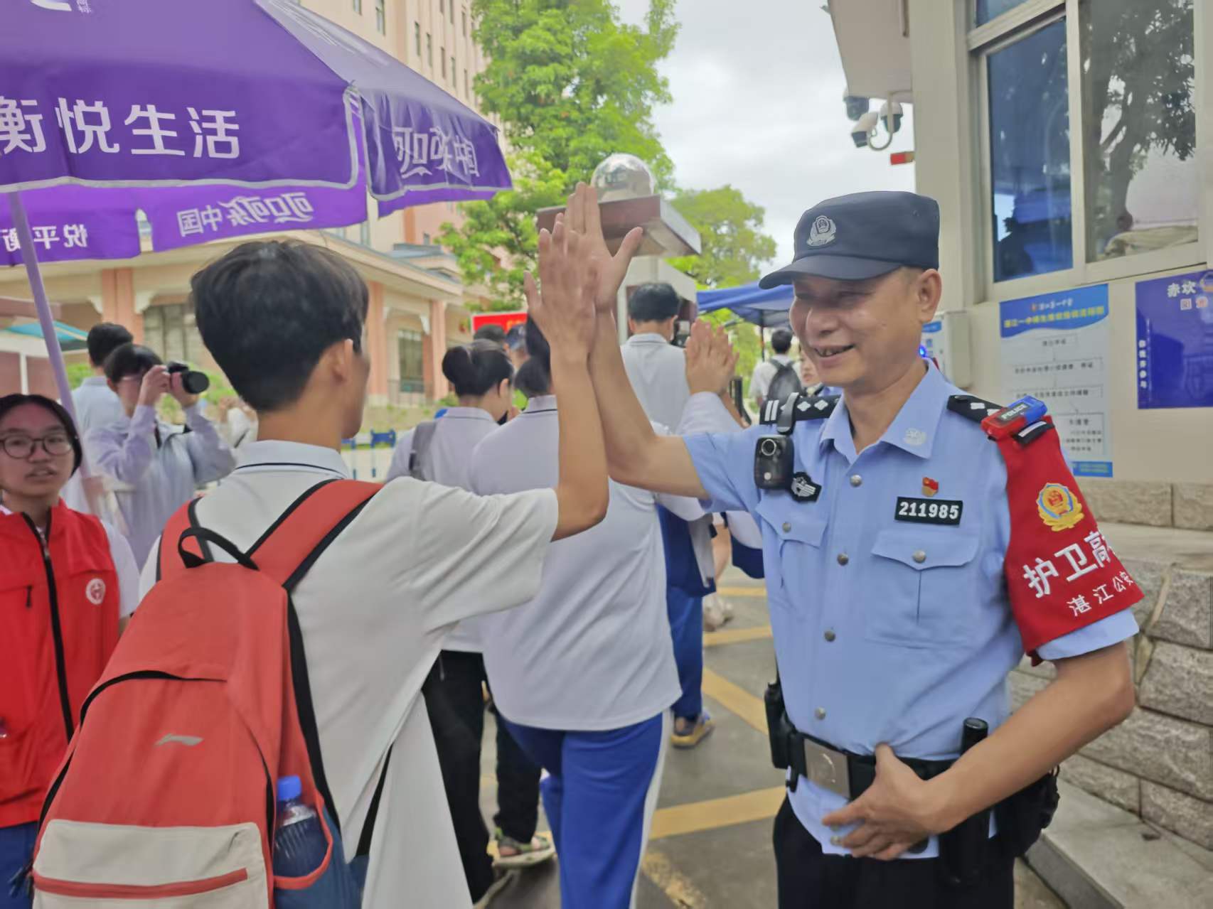 图为湛江市第一中学考点，“211985”警号民警护考，与考生击掌送祝福。湛江市公安局供图