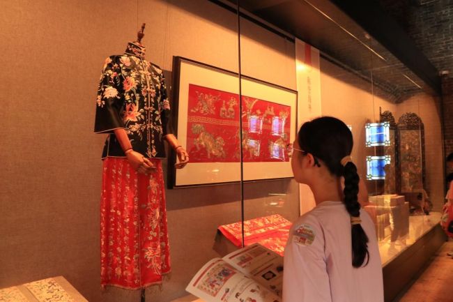 学生对照研学手册,观览展馆中的广绣作品。广东民间工艺博物馆志愿者供图