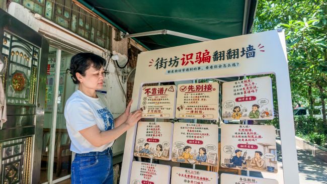 韦素梅把“街坊识骗翻翻墙”九宫格展板摆出来。李文博摄