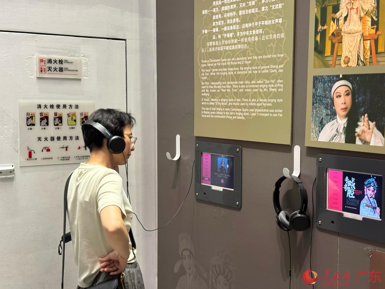 观众佩戴耳机，通过音频交互设备聆听粤剧唱腔，感受粤剧声腔魅力。人民网 李舜摄
